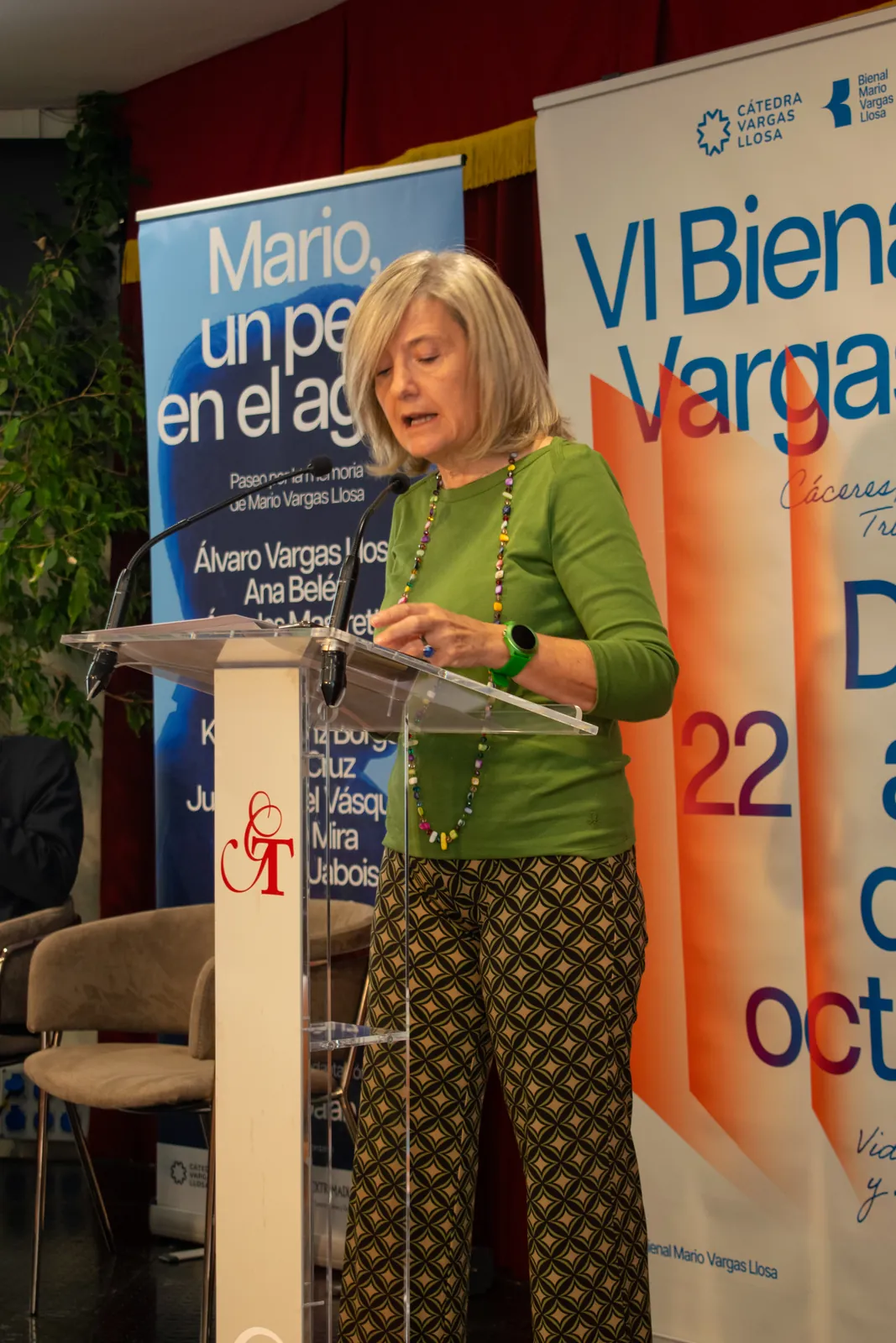 Una ponente hablando en el atril, con los carteles de la Bienal detrás